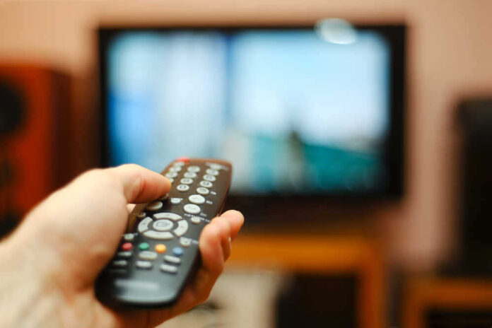 shutterstock_193018853.jpg featured image Hand holding a remote control towards a TV screen.