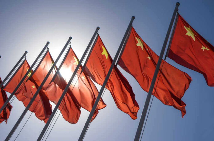 Chinese flags waving under a clear sky.