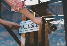 Person flipping closed sign on glass door