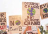 Climate change protest signs being held up outdoors.