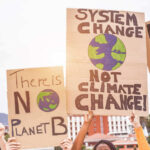 Climate change protest signs being held up outdoors.