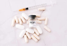 Fentanyl citrate vial surrounded by various pills and syringe.