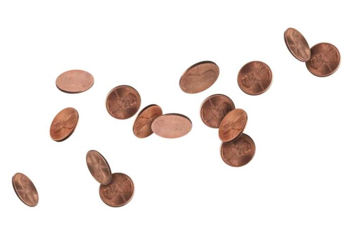 shutterstock_2499160669.jpg featured image Several scattered pennies on a white background