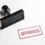 Rubber stamp with the word approved stamped nearby