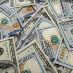 Scattered hundred dollar bills with Benjamin Franklin's portrait.