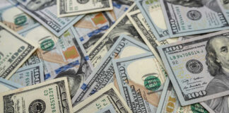 Scattered hundred dollar bills with Benjamin Franklin's portrait.
