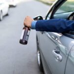 Arm holding beer bottle outside car window