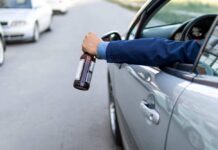 Arm holding beer bottle outside car window