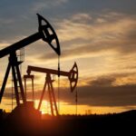 Oil pump jacks silhouetted against sunrise sky