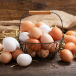 Brown and white eggs in a wire basket.