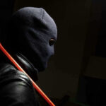Person in ski mask holding a crowbar