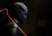 Person in ski mask holding a crowbar