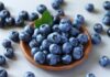 Bowl of blueberries with scattered berries nearby