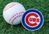 A baseball and a Chicago Cubs logo on green grass