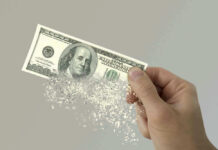 Hand holding a disintegrating hundred dollar bill