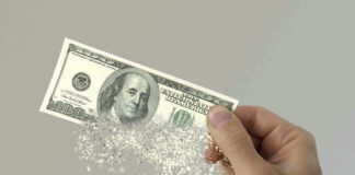 Hand holding a disintegrating hundred dollar bill