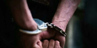 Close-up of hands in handcuffs behind back