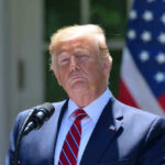 President Donald Trump speaking with US flag in the back
