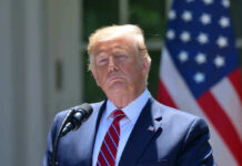 President Donald Trump speaking with US flag in the back