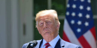 President Donald Trump speaking with US flag in the back