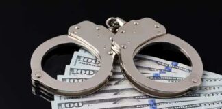 Handcuffs resting on a stack of hundred dollar bills