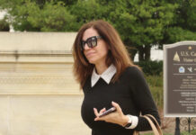 Congresswoman Nancy Mace in sunglasses walking near visitor center sign