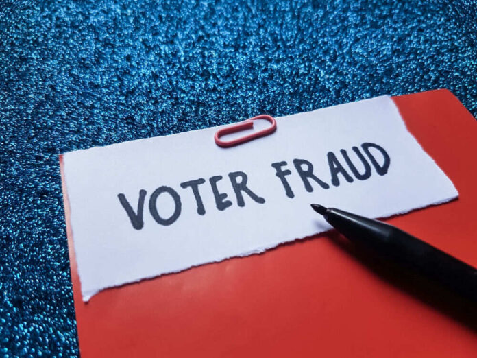 shutterstock_2534479629.jpg Paperclip holding paper labeled voter fraud marker