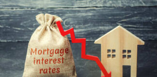 A burlap sack labeled Mortgage interest rates next to a wooden house and a downward red arrow