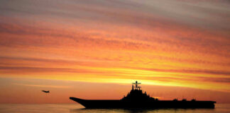 Silhouette of an aircraft carrier at sunset