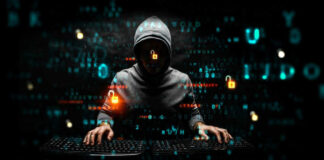 Hacker in dark room with code on screen