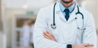 A doctor in a white coat with a stethoscope standing with arms crossed