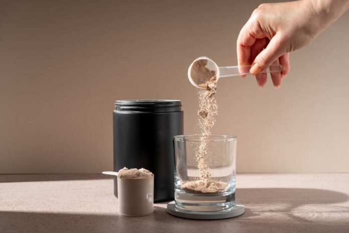Hand scooping protein powder into a glass