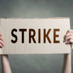 Two hands holding cardboard sign with strike text
