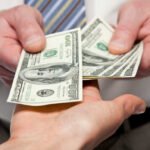 Two hands exchanging cash bills