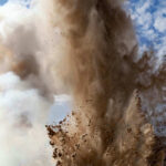 Explosion of dirt and debris against a cloudy sky.