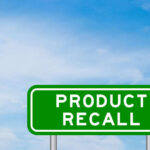 Green sign with product recall text and sky background