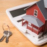 A miniature red house on a calculator with keys nearby