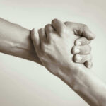 Two hands clasped together in supportive gesture.