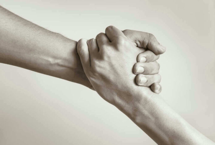 Two hands clasped together in supportive gesture.