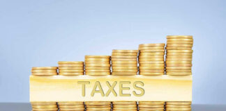 Stacked coins with TAXES on block beneath.