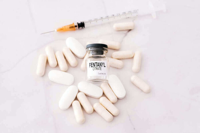 Fentanyl citrate vial surrounded by various pills and syringe.