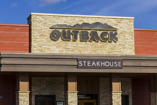 Exterior view of an Outback Steakhouse restaurant with a stone facade