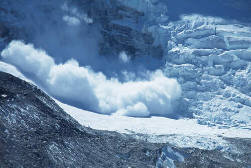 An avalanche cascading down a glacier in a mountainous region