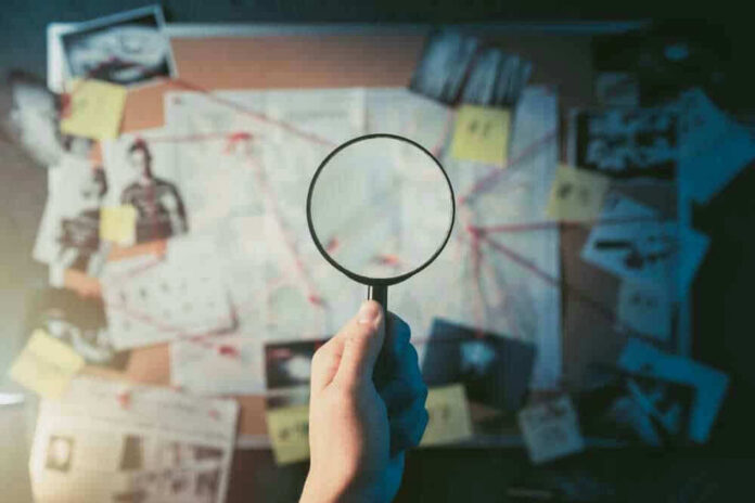 Magnifying glass over investigation board with photos and strings.