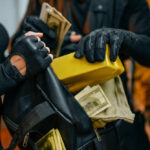 Individuals in black clothing stealing money and items