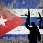Silhouettes of armed figures in front of a weathered Cuban flag