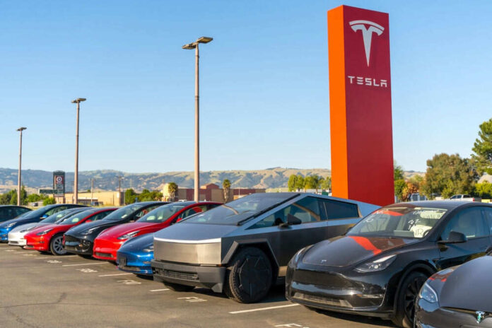 shutterstock_2461159891.jpg Tesla cars parked outside dealership with sign nearby