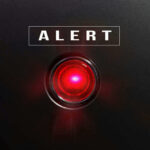Red alert light against black background, text ALERT.