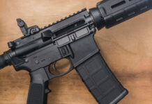 Black rifle on wooden surface close up