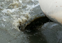 Industrial pipe discharging dark water into a body of water
